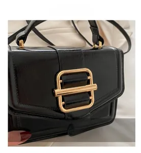 Close-up of black glossy patent leather handbag with a high-quality gold metal buckle