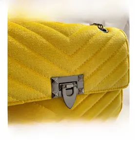 Detail of yellow quilted velvet handbag with black metal clasp and pyramid studs