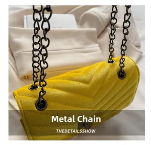 Close-up of yellow chevron quilted velvet bag with dark metal chain strap details