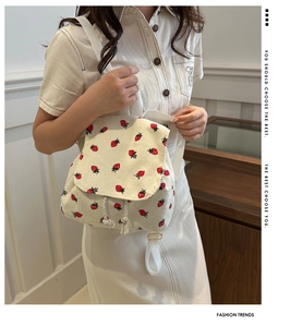 Detail of strawberry embroidery on ivory corduroy backpack with drawstring flap