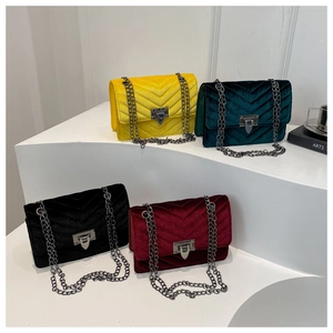 Detailed macro view of velvet crossbody bags with V-shaped quilting and chain straps