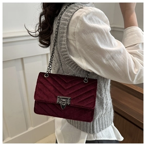 Detailed close-up of burgundy velvet crossbody bag with elegant V-shaped quilting and chain