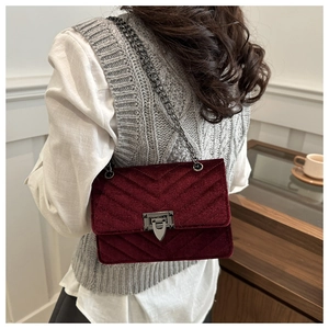 Close-up of burgundy velvet crossbody bag with V-shaped quilting and black chain strap