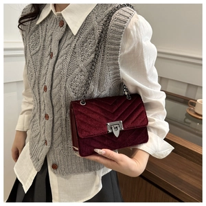 Detail of burgundy velvet crossbody bag featuring V-shaped quilting and silver swivel lock