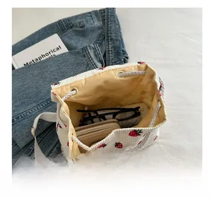 Close-up of strawberry embroidered corduroy bucket bag interior storage and capacity