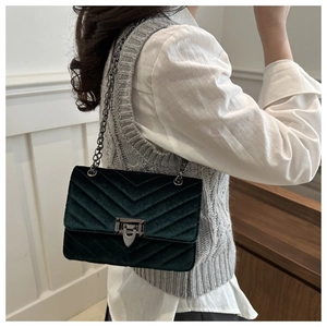 Detail of dark green velvet crossbody bag with V-quilted stitching and metal chain