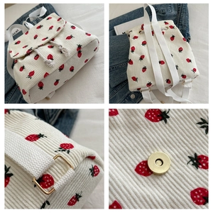 Detail view of strawberry print corduroy backpack featuring magnetic buckle and straps
