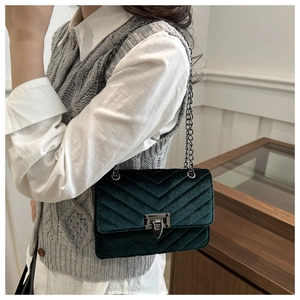 Detail of dark green suede shoulder bag featuring V-shaped quilting and chain strap