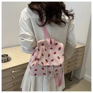 Lifestyle shot of strawberry print pink corduroy backpack with drawstring closure
