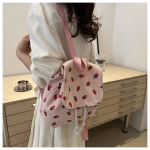 Detailed shot of pink corduroy backpack featuring red strawberry patterns on a model