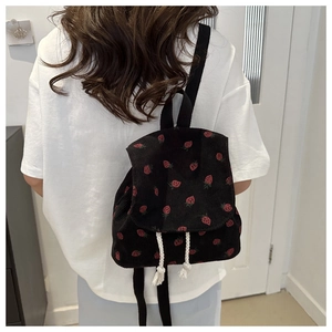 Detail of strawberry print corduroy backpack with drawstring closure and black straps