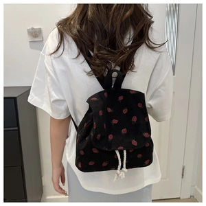 Detail view of mini black corduroy backpack with red strawberry print and drawstring