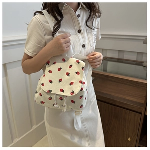 Detail of strawberry print corduroy mini backpack on model in a minimalist setting