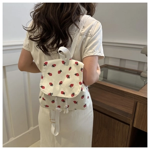Detail of strawberry print corduroy backpack with drawstring flap and adjustable straps