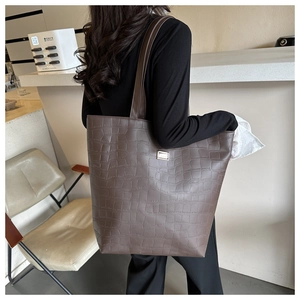 Détail du sac cabas marron foncé avec texture crocodile et boucle en métal argenté sur la bandoulière