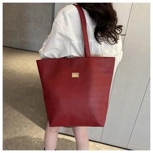 Détail du grand sac cabas rouge avec texture crocodile et décor doré sur chemise blanche
