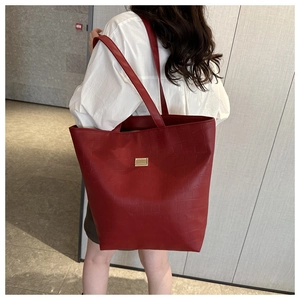 Detail of red crocodile texture tote bag with golden buckle and long shoulder strap