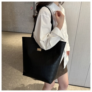 Détail d'un sac cabas noir en cuir embossé crocodile avec boucle dorée chic