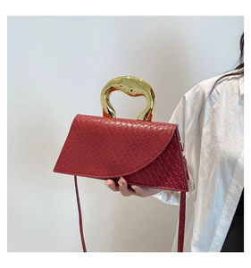 Détail d'un sac rouge en similicuir crocodile avec une large anse ronde dorée
