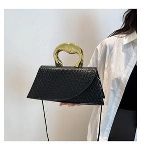 Détail d'un sac à main noir motif crocodile avec poignée métallique dorée moderne