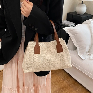 Minimalist beige woven straw tote bag with brown leather handles for summer beach use
