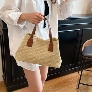 Minimalist straw tote bag with brown leather handles and woven herringbone pattern
