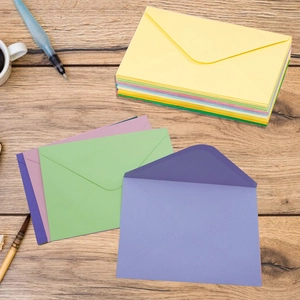 Close-up of colorful kraft paper envelopes on a rustic wooden desk with office tools