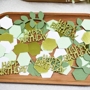 Macro view of green and gold Happy Birthday confetti with glitter hexagon paper decor