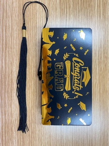 Detalle de tarjeta de graduación en negro y dorado con un elegante pompón negro