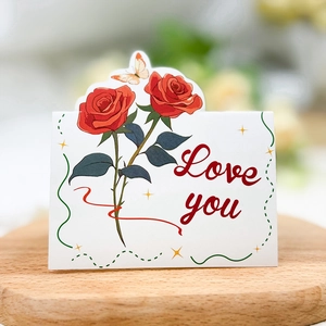 Close-up of a Love You floral card with red roses and a butterfly on a wooden tray