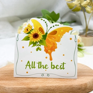 Close-up of a floral greeting card with sunflowers and All the best text on wooden stand