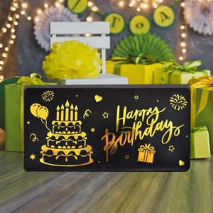 Detalle de tarjeta de cumpleaños negra y dorada con texto Happy Birthday en relieve