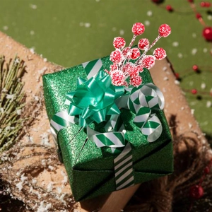 Close-up of frosted red berries on a green gift box with festive Christmas decor