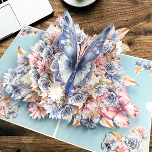 Détail d'une carte 3D avec papillon bleu et motifs floraux en papier découpé