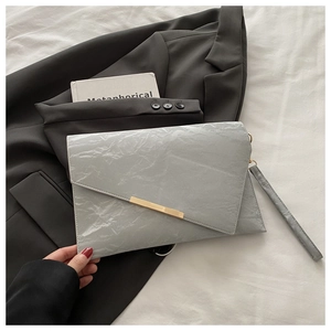 Détail du sac enveloppe gris plissé avec bordure dorée élégante et bandoulière