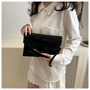 Détail de la pochette enveloppe noire à texture froissée et bordure en métal doré