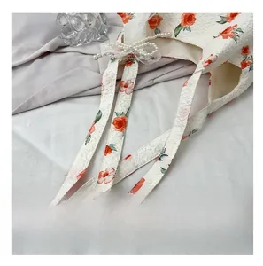 Detail of floral jacquard tote bag with pearl chain handle and lace trim