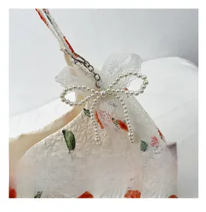 Detail of rose floral fabric tote with pearl butterfly lace charm and texture