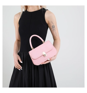 Dettaglio borsa a mano rosa in pelle con chiusura dorata indossata da modella in nero