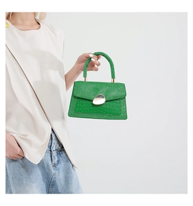 Nahaufnahme der grünen Glitzer-Handtasche mit Krokodilmuster und Kiesel-Metallschloss
