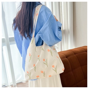 Detail of white textured fabric tote bag featuring vibrant orange tulip floral patterns