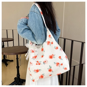 Detail of floral tote bag showing textured rose fabric with lace bow and pearl charm