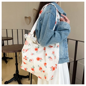 Detail of floral jacquard tote bag with white lace bow and elegant pearl charm