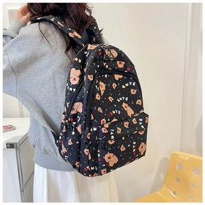 Detail of cute bear pattern and CUTE text on black fashion backpack for students