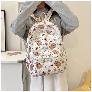 Detail of white canvas backpack with brown bear prints and CUTE text on a model