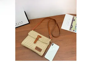 Top view of beige woven crossbody bag with brown leather strap next to a smartphone