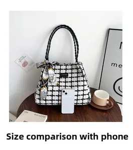 Détail du sac cabas en tweed à carreaux avec foulard et anses tissées sur une table
