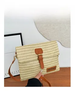 Detail of hand-woven straw shoulder bag with beige and green zigzag texture and leather strap