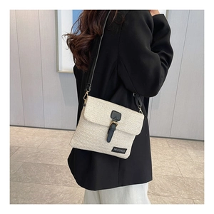 Close-up of beige woven crossbody bag with straw texture and black faux leather strap buckle