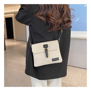 Rear view of model wearing cream woven crossbody bag with black leather trim and strap